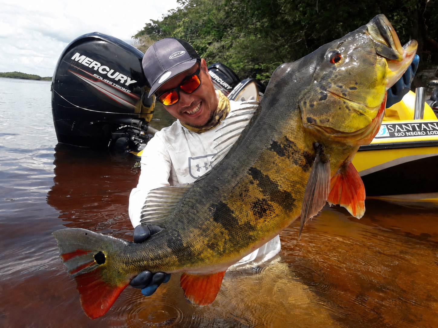 大型のピーコックバスを抱えるBassin’Heavenスタッフ